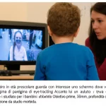 Un bambino in età prescolare guarda con interesse uno schermo dove viene proiettato un paradigma di eye-tracking. Accanto a lui, un adulto osserva con fare supportivo. L'ambiente è accogliente e studiato per i bambini. Obiettivo prime, 35mm, profondità di campo, illuminazione da studio morbida.