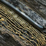 Visualizzazione 3D fotorealistica di un gel di nanosilice che si propaga attraverso una formazione rocciosa eterogenea all'interno di un pozzo petrolifero, con zone di diversa permeabilità evidenziate da texture e colori differenti. L'immagine dovrebbe avere un effetto "spaccato" della roccia per mostrare l'interno. Macro lens, 100mm, high detail, precise focusing, controlled lighting per enfatizzare la complessità della struttura rocciosa e la precisione del gel.