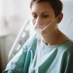 A patient receiving high-flow nasal cannula therapy in a hospital room, 35mm portrait, shallow depth of field, controlled lighting.
