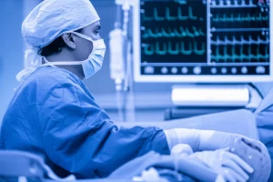 Primo piano, obiettivo prime 35mm, di un cardiochirurgo pediatrico che esamina attentamente i dati di un monitor in sala operatoria durante un intervento al cuore su un neonato (modello o contesto simulato), luce controllata, profondità di campo che sfoca lo sfondo, toni duotone blu e grigio per un'atmosfera clinica ma concentrata.