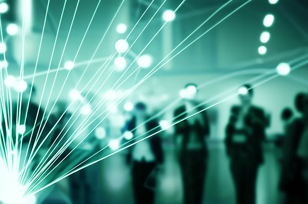 Immagine concettuale di una rete di persone connesse, che simboleggia lo scambio di conoscenze e il supporto reciproco in una comunità urbana. Prime lens, 35mm, duotone blu e verde, profondità di campo per evidenziare le connessioni.