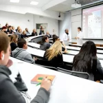 Aula universitaria moderna con studenti di medicina attenti durante una lezione di anatomia, proiettore acceso sullo sfondo mostra una slide complessa, luce ambientale brillante, obiettivo grandangolare 24mm, messa a fuoco nitida sull'intera scena.