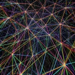 Illustrazione concettuale avanzata di una simulazione di trasporto di particelle su una mesh poliedrica Voronoi tridimensionale. Linee di flusso luminose e colorate attraversano le celle trasparenti della mesh, suggerendo movimento e direzione. Wide-angle lens, 10mm, long exposure effect per creare scie luminose fluide, sharp focus sulla struttura della mesh Voronoi, sfondo scuro per enfatizzare il flusso.