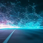 Immagine fotorealistica di confini aziendali stilizzati che si dissolvono gradualmente in una rete luminosa e interconnessa di particelle digitali che si estende globalmente, simboleggiando l'espansione oltre i limiti tradizionali grazie all'innovazione aperta. Scatto grandangolare, obiettivo 20mm, lunga esposizione per creare scie luminose dinamiche, focus nitido sulla transizione tra solido e digitale.