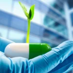 Immagine simbolica che mostra una mano guantata da medico che tiene delicatamente un germoglio verde che cresce da una capsula medica stilizzata, su uno sfondo sfocato di un moderno ospedale, obiettivo prime 35mm, profondità di campo ridotta, illuminazione morbida e naturale.
