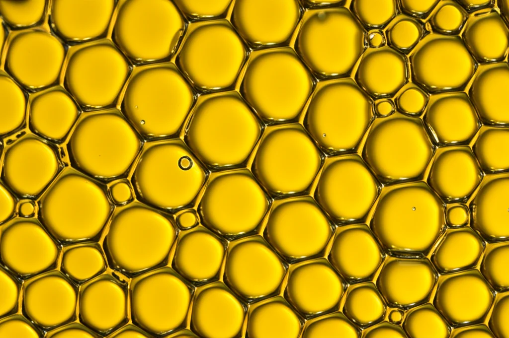Macro fotografia di molecole di tensioattivi zwitterionici bio-based che si auto-assemblano all'interfaccia olio-acqua, illuminazione controllata per evidenziare i dettagli delle micelle, obiettivo macro 100mm, alta definizione.