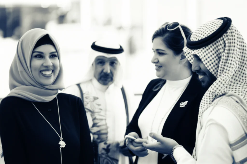 Immagine fotorealistica di un gruppo eterogeneo di persone in Arabia Saudita, alcune sorridenti, altre che conversano, in un ambiente moderno e luminoso che suggerisce benessere. Prime lens, 35mm, depth of field, luce naturale diffusa, duotone seppia e blu.