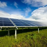 Installazione di pannelli fotovoltaici di diverse tecnologie (silicio monocristallino, policristallino, film sottile come silicio amorfo e CIS) in un campo sperimentale in un lussureggiante ambiente tropicale del Brunei Darussalam, sotto un cielo parzialmente nuvoloso che suggerisce variabilità di insolazione. Wide-angle, 10-24mm, sharp focus, per catturare l'estensione dell'impianto e il contesto ambientale umido e caldo.