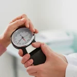 Fotografia ritratto, primo piano sulle mani di un anziano mentre un medico ne valuta la forza della presa con un dinamometro, obiettivo primario 35mm, profondità di campo, illuminazione calda e rassicurante in uno studio medico, focus sull'interazione e sullo strumento.