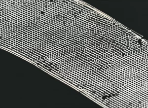 Visualizzazione fotorealistica di un film sottile di MXene liquido-cristallino, con una struttura interconnessa a livello molecolare grazie a polimeri bio-ispirati di norepinefrina, che mostra il potenziale per dispositivi di accumulo energetico avanzati. Dettaglio macro con illuminazione laterale per enfatizzare la texture e l'allineamento, obiettivo macro 60mm, alta definizione.