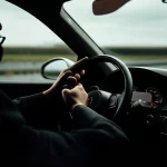 Un conducente attento e vigile grazie a un sistema di monitoraggio della stanchezza hi-tech integrato nel cruscotto, prime lens 35mm, depth of field, illuminazione controllata che evidenzia i sensori discreti e un'interfaccia utente futuristica.