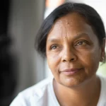 Photorealistic portrait, 35mm lens, shallow depth of field, of a person reflecting on their journey with HIV, conveying resilience and hope after advanced disease diagnosis.