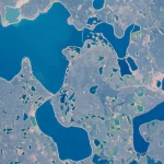 Immagine satellitare Sentinel-2 di un paesaggio terrestre con fiumi serpeggianti e laghi di varie dimensioni, alcuni con bordi complessi e vegetazione ripariale. La scena è illuminata dalla luce solare diffusa, creando riflessi sull'acqua. Wide-angle lens, 20mm, sharp focus, long exposure per rendere l'acqua liscia, mostrando la sfida della segmentazione precisa dei corpi idrici.