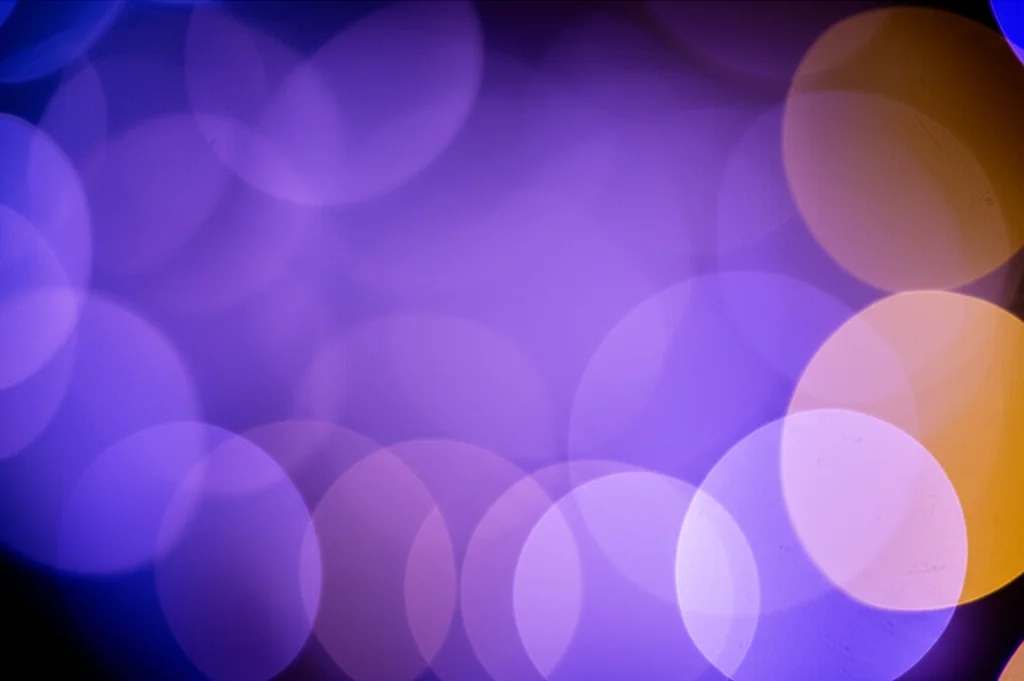 Una rappresentazione artistica e astratta di multipli (più di due) cerchi fuzzy colorati e semitrasparenti che si sovrappongono e si intersecano in uno spazio n-dimensionale stilizzato. L'immagine dovrebbe evocare complessità e interconnessione. Lente prime 35mm, profondità di campo media, illuminazione drammatica con luci e ombre per enfatizzare le dimensioni, colori duotone viola e arancione.