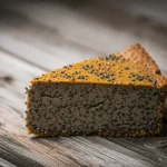 Immagine fotorealistica di una deliziosa fetta di torta senza glutine con semi di chia visibili e una texture invitante data dalla farina di lenticchie, posizionata su un tavolo di legno rustico, obiettivo macro 100mm, alta definizione, messa a fuoco precisa, illuminazione naturale controllata.