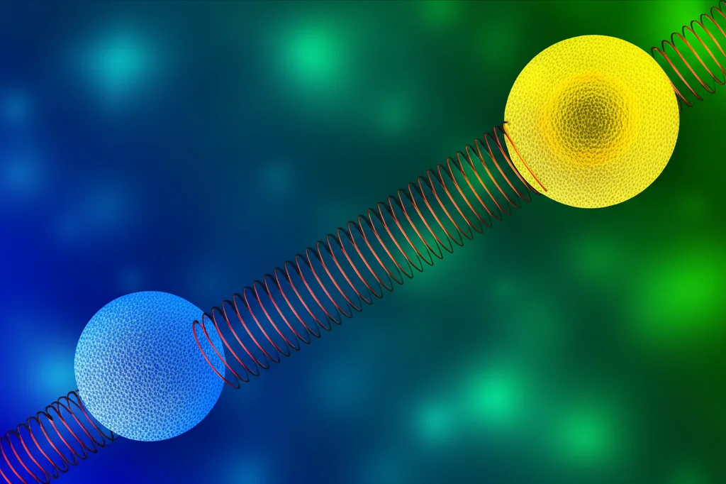 Due nanoparticelle levitate, una blu che simboleggia il rumore e una gialla che mostra uno spostamento coerente, collegate da una molla rossa stilizzata (forza di Coulomb non lineare). Sfondo scuro con dettagli verdi per la forza di compensazione. Illuminazione drammatica. Macro lens, 70mm, high detail, precise focusing, controlled lighting, duotone blu scuro e giallo brillante.