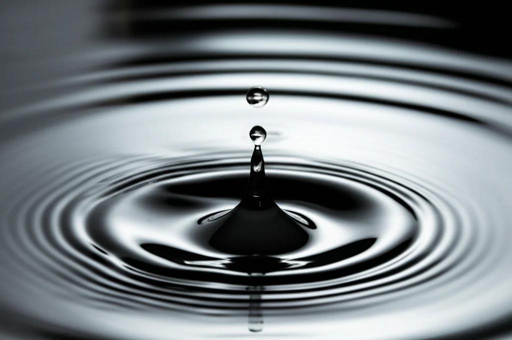Fotografia macro di una goccia d'acqua che cade su una superficie liscia, creando cerchi concentrici perfetti, alta velocità di scatto per congelare il momento, illuminazione controllata per esaltare la trasparenza e i riflessi, obiettivo 100mm. Rappresenta la regolarità e la simmetria delle soluzioni trovate.