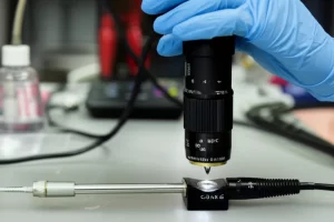 Immagine fotorealistica di un campione di roccia carbonatica bioturbata in laboratorio, con un permeametro portatile che effettua una misurazione spot sulla sua superficie. Macro lens, 60mm, high detail, precise focusing, controlled lighting per evidenziare la texture della roccia e lo strumento.