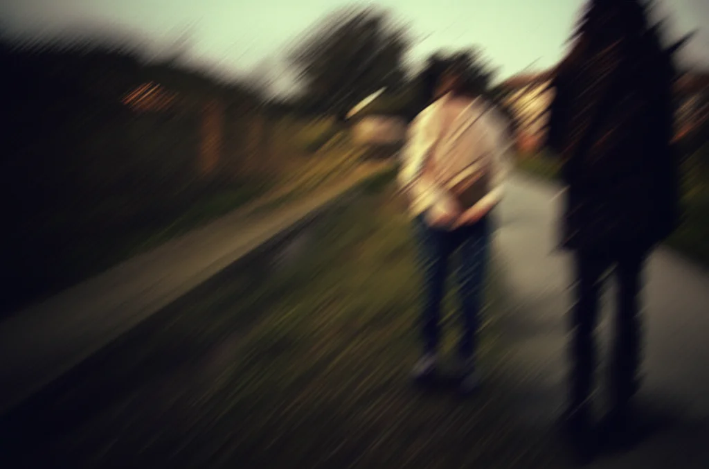 Due giovani sagome si stagliano contro un cielo al tramonto, una conforta l'altra che appare triste. Simboleggia il supporto e l'empatia necessari per affrontare la depressione. Wide-angle lens, 18mm, long exposure, colori caldi e avvolgenti del crepuscolo.