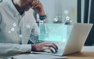Imprenditore di una PMI pensieroso davanti a un grafico discendente sul suo laptop, con icone stilizzate di crowdfunding e catene spezzate sullo sfondo a simboleggiare sia l'opportunità che le sfide finanziarie legate all'ECF. Fotografia realistica, obiettivo 50mm prime, profondità di campo ridotta per focalizzare sull'imprenditore, luce da ufficio soffusa.