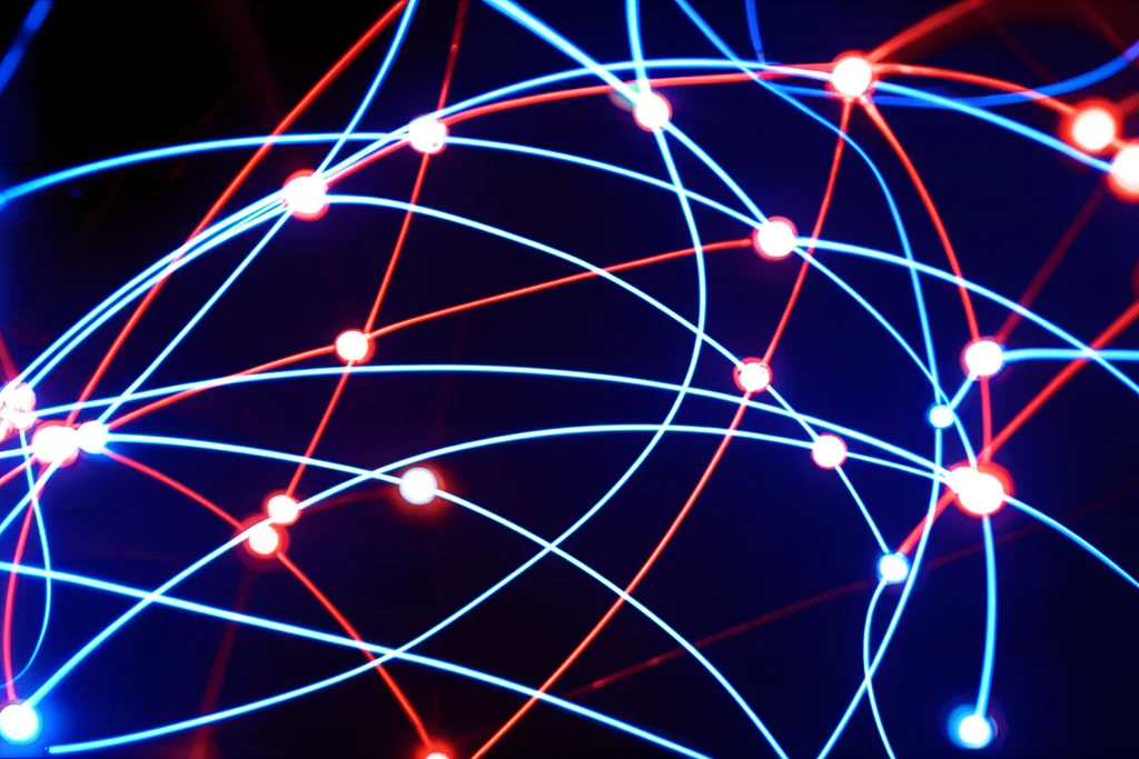 A grandangola, lente da 15 mm, rappresentazione artistica astratta di percorsi metabolici interconnessi con nodi luminosi che rappresentano lipidi come colina e glicerofosfolipidi. Alcuni percorsi sono evidenziati in rosso (disregolato) e altri in blu (normale). Linee fluide e fluide che collegano i nodi, su uno sfondo scuro, sottilmente strutturato, suggerendo complessità e interconnessione. Effetto a lungo esposizione per gli elementi luminosi.