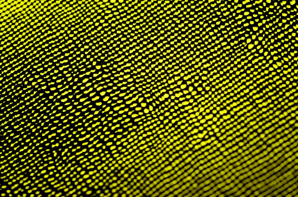 Macro fotografia, 70mm lens, di un innovativo materiale carbogel scuro e poroso che emette una debole luminescenza mentre converte il calore in elettricità, simboleggiando l'energia sostenibile, high detail, precise focusing, illuminazione drammatica e controllata per enfatizzare la texture.