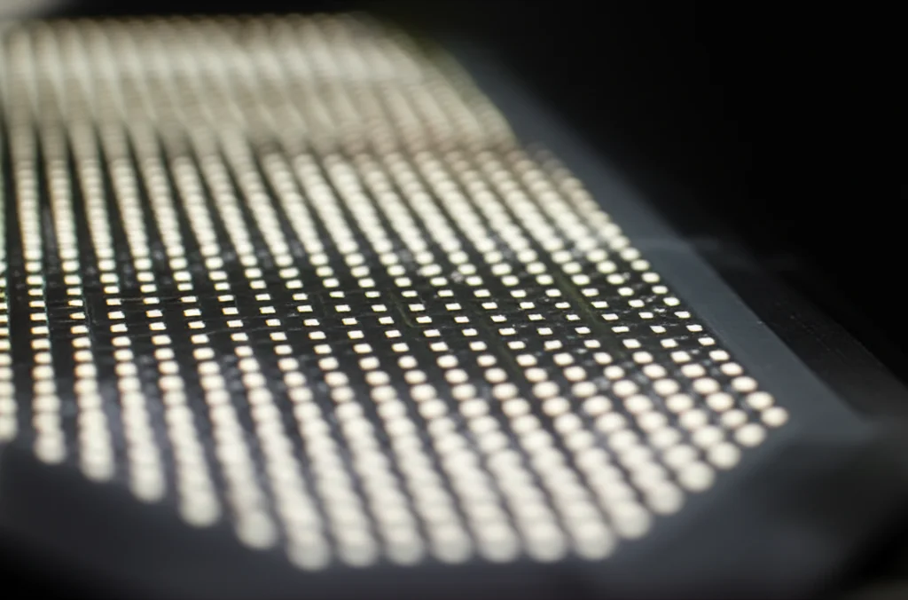 Immagine macro ad alta definizione di un array di micro-LED integrati su un substrato polimerico flessibile, illuminazione controllata per evidenziare i dettagli dei circuiti e la texture del materiale, focale 100mm, alta precisione di messa a fuoco.