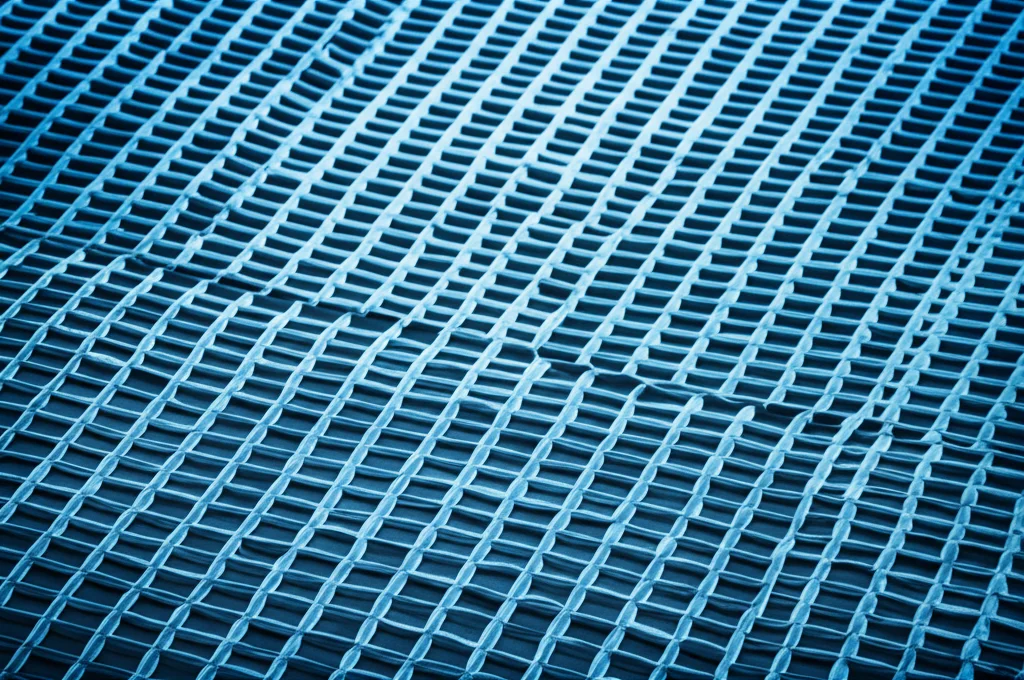 Macro fotografia di una superficie di membrana di nanofiltrazione high-tech, illuminazione da laboratorio controllata e precisa, obiettivo macro 100mm, mostrando la texture intricata e i pori su scala nanometrica, con un leggero bagliore bluastro che suggerisce il flusso d'acqua purificata.