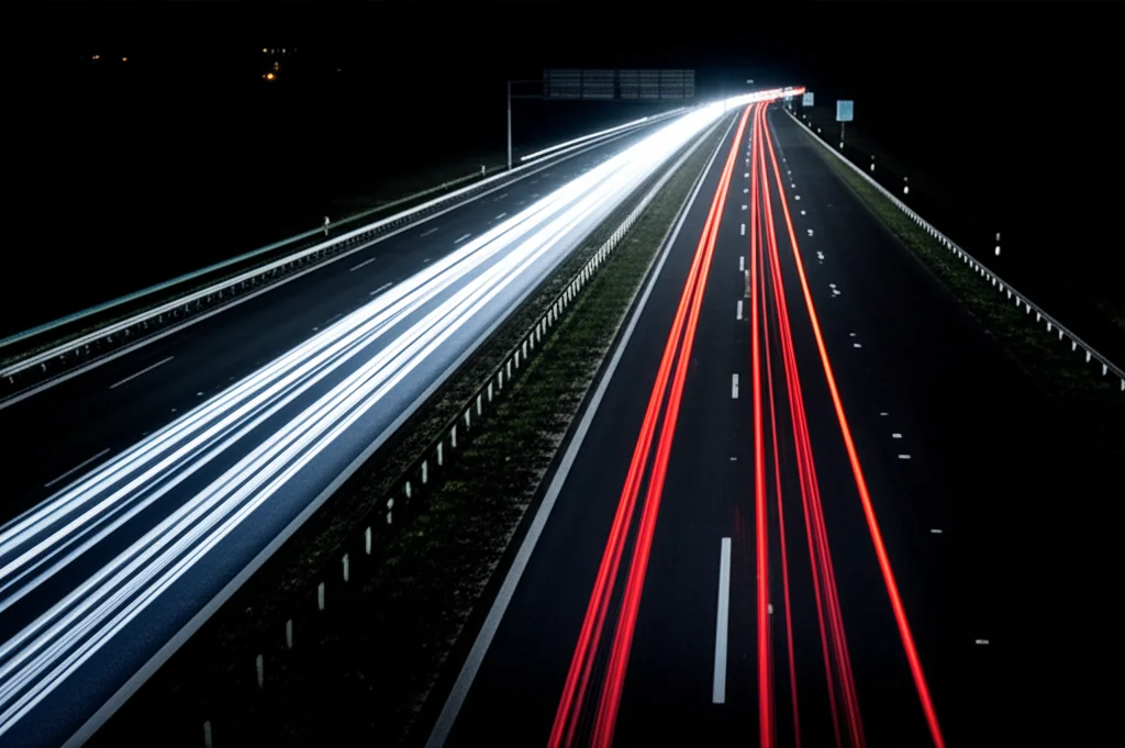 Fotografia realistica di un'autostrada di notte, con le linee della corsia chiaramente illuminate e rilevate da un sistema di assistenza alla guida. Le luci dei fari dell'auto creano un effetto di profondità. Obiettivo teleobiettivo zoom, 100-400mm, per comprimere la prospettiva e concentrarsi sulle linee distanti, velocità dell'otturatore veloce per congelare il movimento.