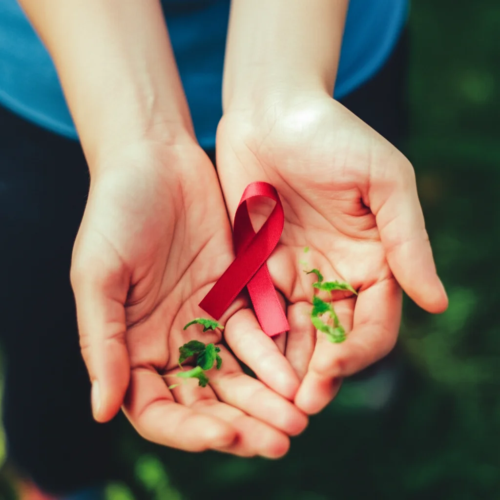 Un'immagine macro di due mani che si stringono delicatamente, una indossa un piccolo nastro rosso simbolo della lotta all'HIV, l'altra tiene un piccolo germoglio verde simbolo di salute mentale e speranza. Illuminazione controllata e precisa, alto dettaglio, sfondo sfocato per enfatizzare le mani.
