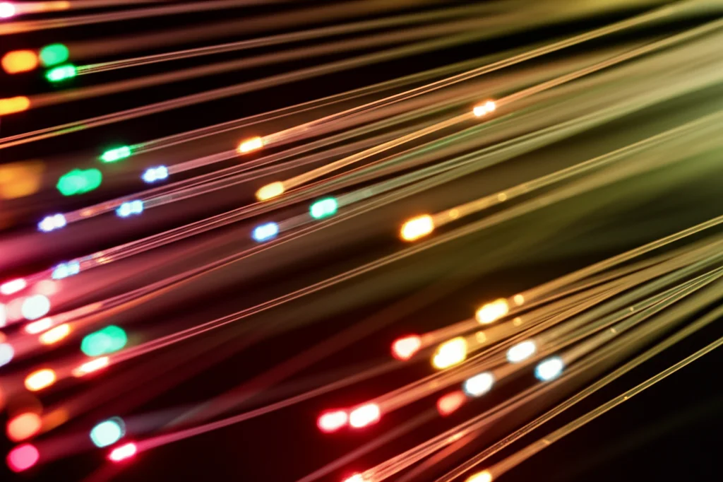 Un'immagine macro astratta di fotoni colorati che interagiscono come molecole in una reazione chimica all'interno di una fibra ottica multimodale, illuminazione laterale controllata per evidenziare le texture, alta definizione dei dettagli dei 'fotoni', obiettivo macro 100mm.