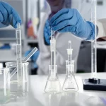Immagine fotorealistica, lente Prime da 35 mm, profondità di campo. Le mani guantate di uno scienziato gestiscono con cura sia un componente a setaccio aperto sia un supporto per filtro in linea chiuso su una panca da laboratorio con becher di acqua limpida nelle vicinanze, simboleggiando il confronto dei metodi di campionamento microplastici per la qualità dell'acqua potabile.