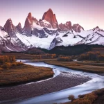 Panoramica spettacolare di una catena montuosa innevata nell'ovest degli Stati Uniti al tramonto. In primo piano scorre un fiume limpido e serpeggiante, originato dallo scioglimento delle nevi visibili sulle cime. La luce calda del sole illumina le vette. Obiettivo grandangolare 10mm, paesaggio, messa a fuoco nitida, lunga esposizione per acqua liscia, colori vividi del tramonto.
