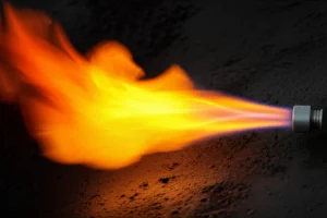 Immagine fotorealistica, teleobiettivo zoom lente (150 mm), catturando il bordo affilato e luminoso di una parte anteriore a fiamma controllata che si muove su una superficie scura e strutturata, che simboleggia un limite libero nella teoria della combustione, velocità dell'otturatore rapida per il congelamento del movimento, focalizzazione del monitoraggio dell'azione.