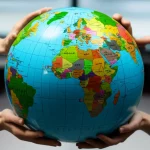 Fotografia grandangolare di un globo terrestre stilizzato composto da tante piccole mani di colori diversi che si intrecciano, simboleggiando l'unità nella diversità globale. Sfondo neutro e luminoso, obiettivo grandangolare 24mm, messa a fuoco nitida su tutto il globo, colori vivaci ma armoniosi.