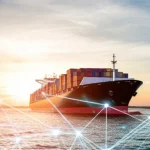 Immagine fotorealistica di una nave portacontainer moderna che naviga in mare aperto durante un tramonto spettacolare, sovrapposta a una griglia digitale astratta e luminosa che simboleggia una rete informatica complessa sotto analisi o attacco, obiettivo grandangolare 15mm per catturare l'ampiezza della scena, contrasto tra i colori caldi del cielo e i toni freddi della griglia digitale, alta definizione e dettaglio nitido.