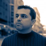 Portrait photography, a Lebanese adult looking thoughtfully into the distance, 35mm prime lens, with a slightly blurred background of a generic urban Lebanese setting. Duotone effect, perhaps sepia and blue, to convey a mix of resilience and underlying melancholy. Depth of field focusing on the subject's eyes.
