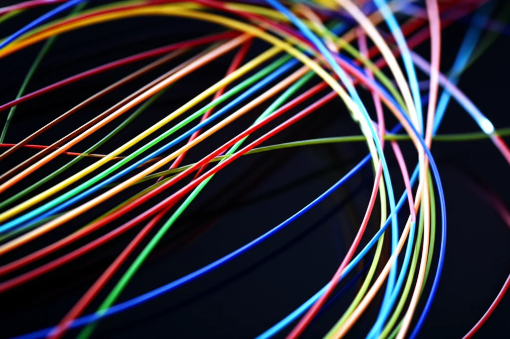 Immagine macro astratta di fili luminosi intrecciati che formano una rete complessa ma coerente, su sfondo scuro. Obiettivo macro 100mm, illuminazione controllata per evidenziare i punti di connessione, alta definizione. Simboleggia la complessità delle credenze, del significato e del benessere mentale che si intrecciano.