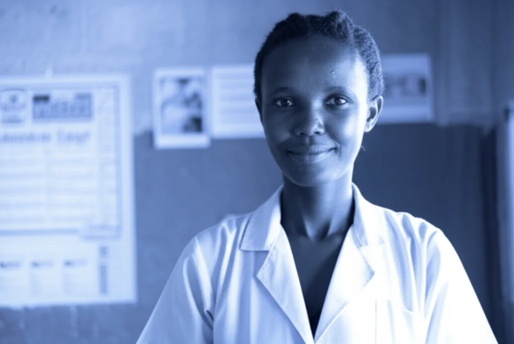 Fotografia ritratto di un'operatrice sanitaria ugandese sorridente ma pensierosa, che indossa un camice, all'interno di una clinica rurale. Luce naturale morbida, obiettivo da 35mm, profondità di campo ridotta per sfocare lo sfondo. Duotone blu e grigio.