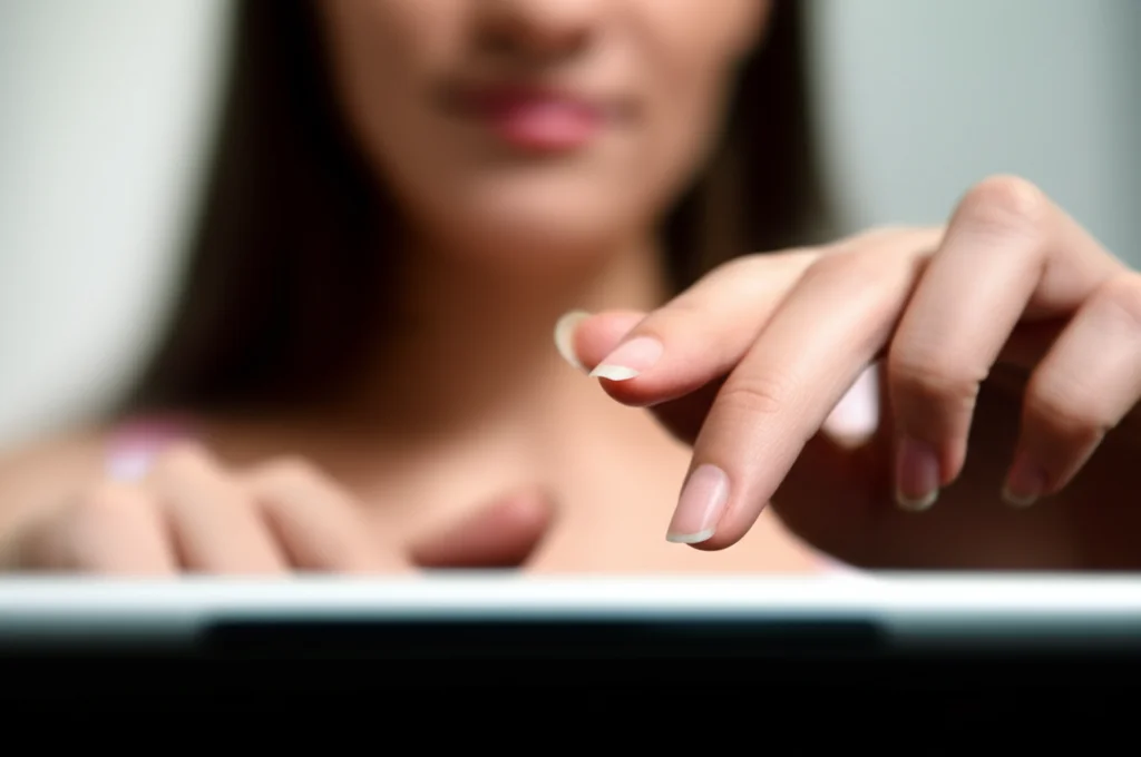 Primo piano delle mani di una persona che navigano su un sito di online banking su un tablet, con un'espressione concentrata ma fiduciosa sul volto parzialmente visibile. Illuminazione controllata, obiettivo macro 90mm, alta definizione per i dettagli dello schermo e delle dita.