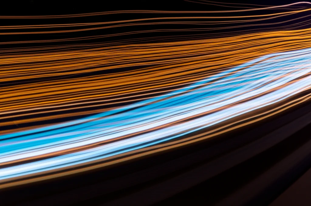 Immagine concettuale che rappresenta il flusso del tempo intrecciato con l'analisi linguistica. Flussi astratti di luce o dati che scorrono cronologicamente, sovrapposti a deboli pattern di testo o onde sonore. Obiettivo grandangolare, 20mm, lunga esposizione, elementi fluidi e levigati, focus nitido sui dettagli centrali, colori vibranti ma armoniosi.