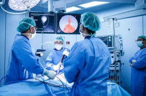 Immagine fotorealistica di una sala operatoria ibrida durante una procedura TEVAR complessa su un paziente con arco aortico destro. Si vedono schermi angiografici che mostrano l'anatomia vascolare anomala e il team medico concentrato. Telephoto zoom, 150mm, action tracking, high detail.