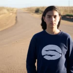A young person with diabetes, 35mm portrait, standing at a crossroads, symbolizing the transition from pediatric to adult healthcare, depth of field.