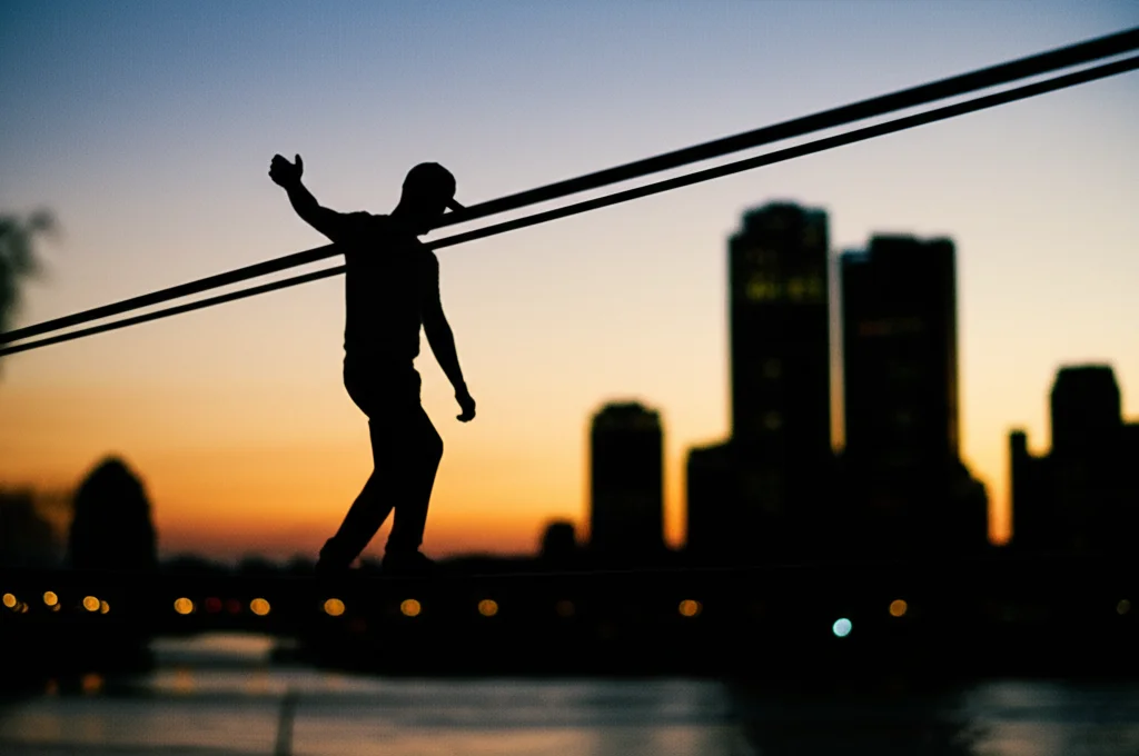 Foto paesaggistica grandangolare, silhouette di una persona che cammina con cautela su una corda tesa tra due punti astratti, contro uno skyline cittadino leggermente sfocato al crepuscolo, obiettivo grandangolare 20mm, messa a fuoco nitida sulla silhouette, per trasmettere equilibrio e rischio.