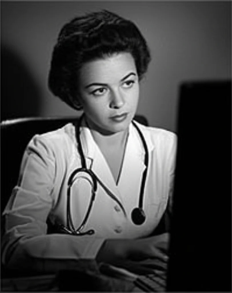 Fotografia in bianco e nero, stile film noir, ritratto 35mm di un medico donna pensierosa che guarda dei grafici su un computer in un ufficio scarsamente illuminato, profondità di campo, focus sugli occhi.