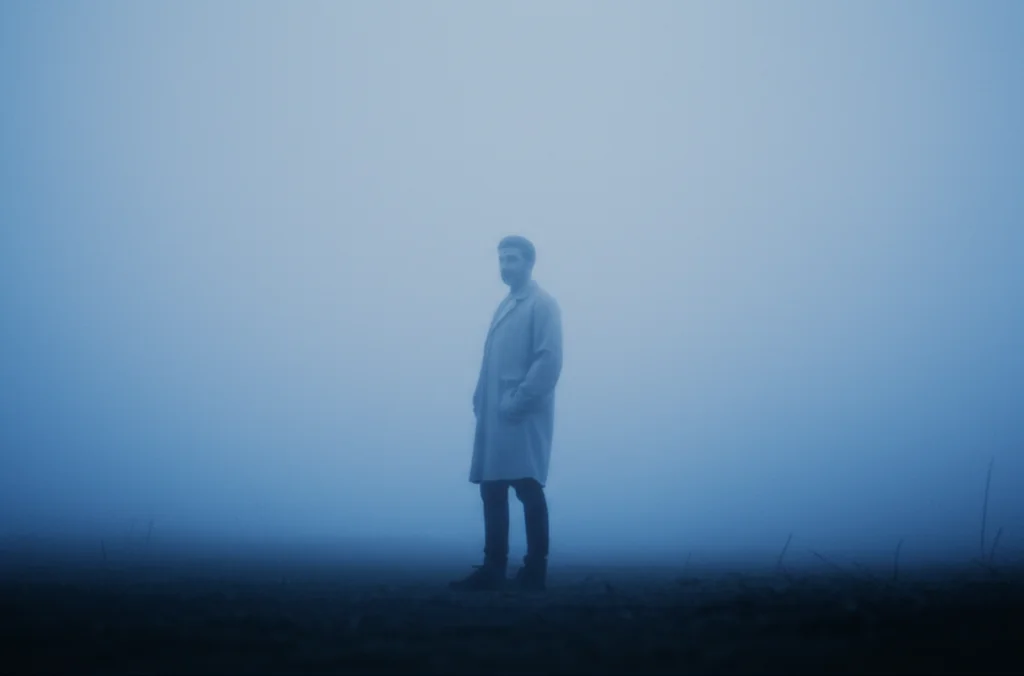 A figure standing in a misty, undefined space, 35mm portrait, depth of field, blue and grey duotones