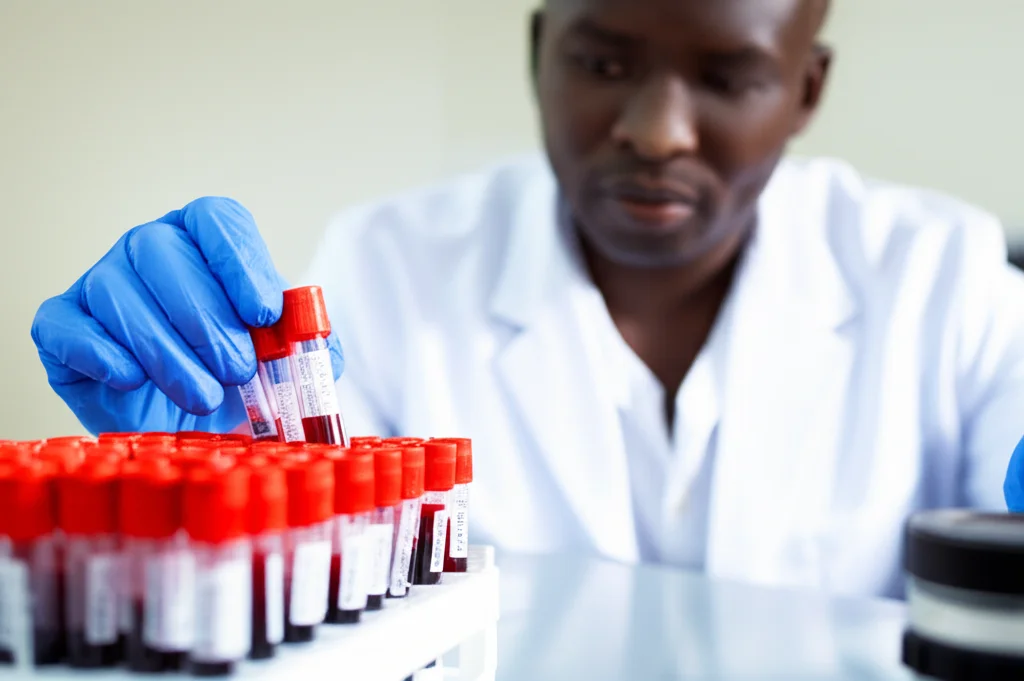 A photorealistic scene in a research lab in Senegal, showing a scientist carefully handling blood samples, with a shallow depth of field focusing on the samples, using a 35mm lens.