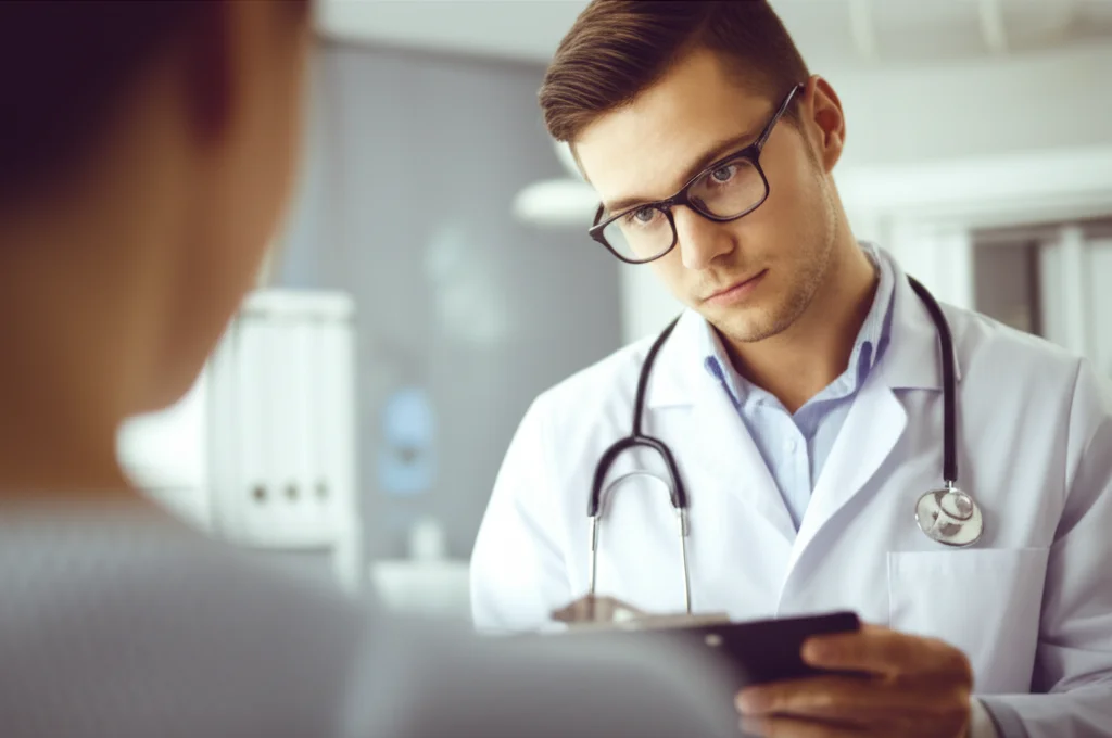 A portrait photograph captured with a 35mm prime lens, showing a medical professional (doctor or nurse) looking attentively at a patient's chart, with a shallow depth of field blurring the background hospital environment. The lighting is controlled to highlight the focused expression.