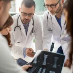 A team of medical professionals discussing a complex pediatric foot reconstruction case using imaging scans, portrait photography, 35mm, depth of field.