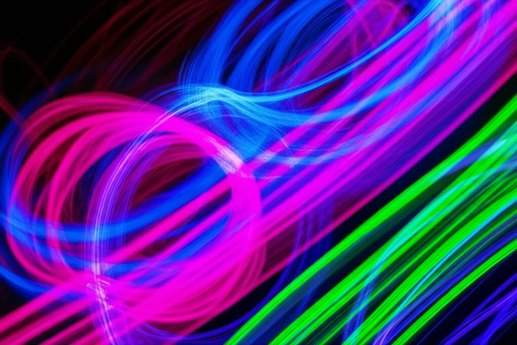 A dynamic, abstract representation of quantum Hamiltonians commuting. Swirling, colorful energy fields (representing Hamiltonians) interpenetrate without clashing, suggesting harmony and integrability. Telephoto zoom, 200mm, fast shutter speed to capture the motion, with vibrant neon colors against a dark void.
